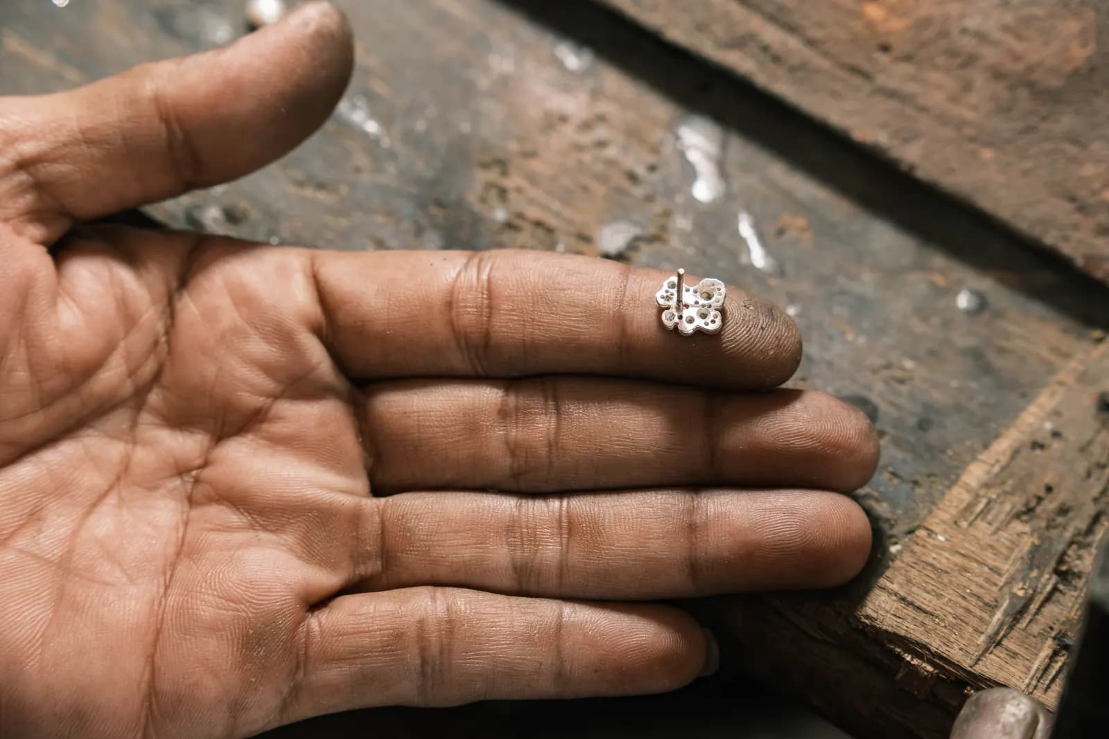 Open palm with a tiny flower ring on a fingertip over the bench