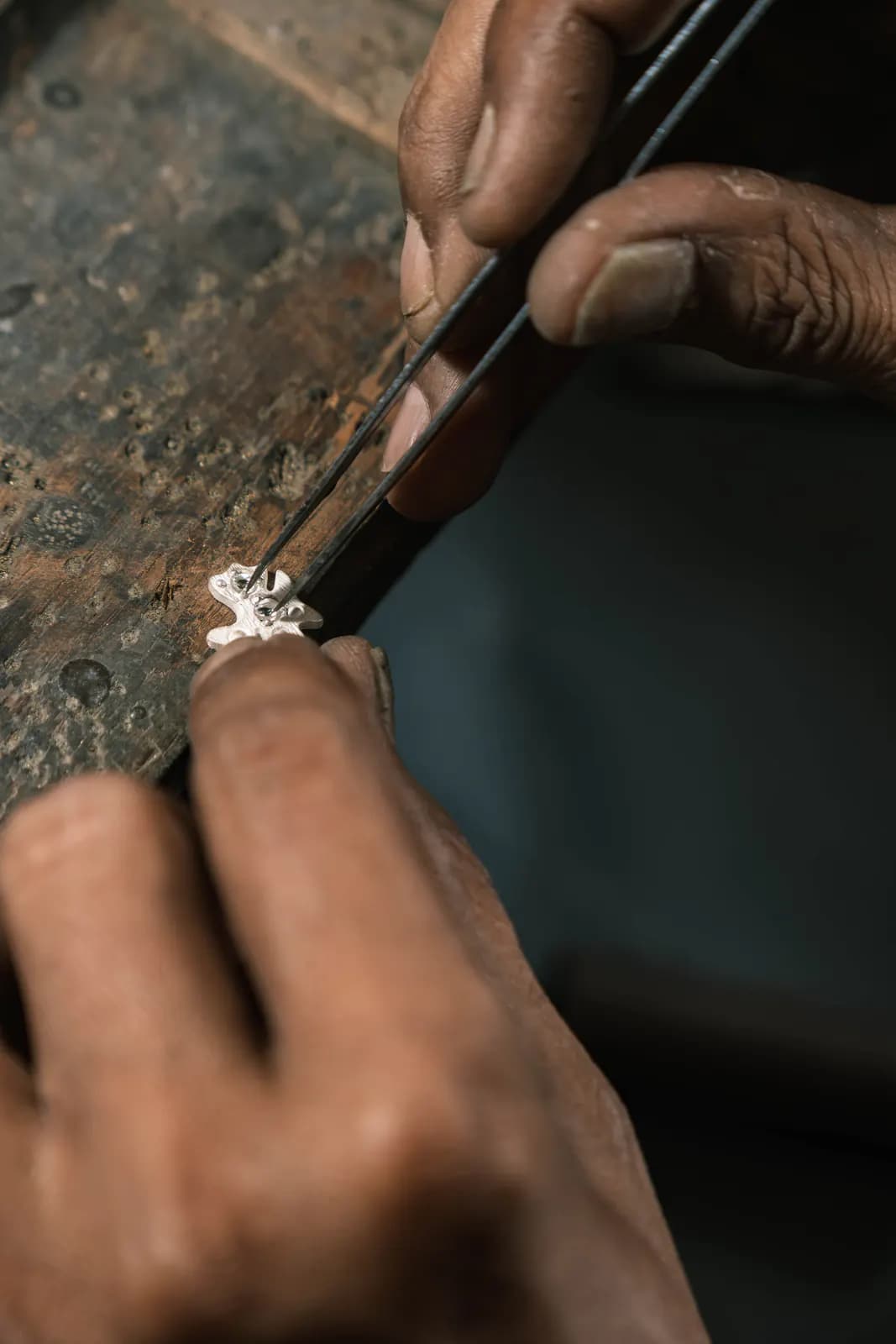 Tweezers adjusting a flower-shaped piece on the workbench