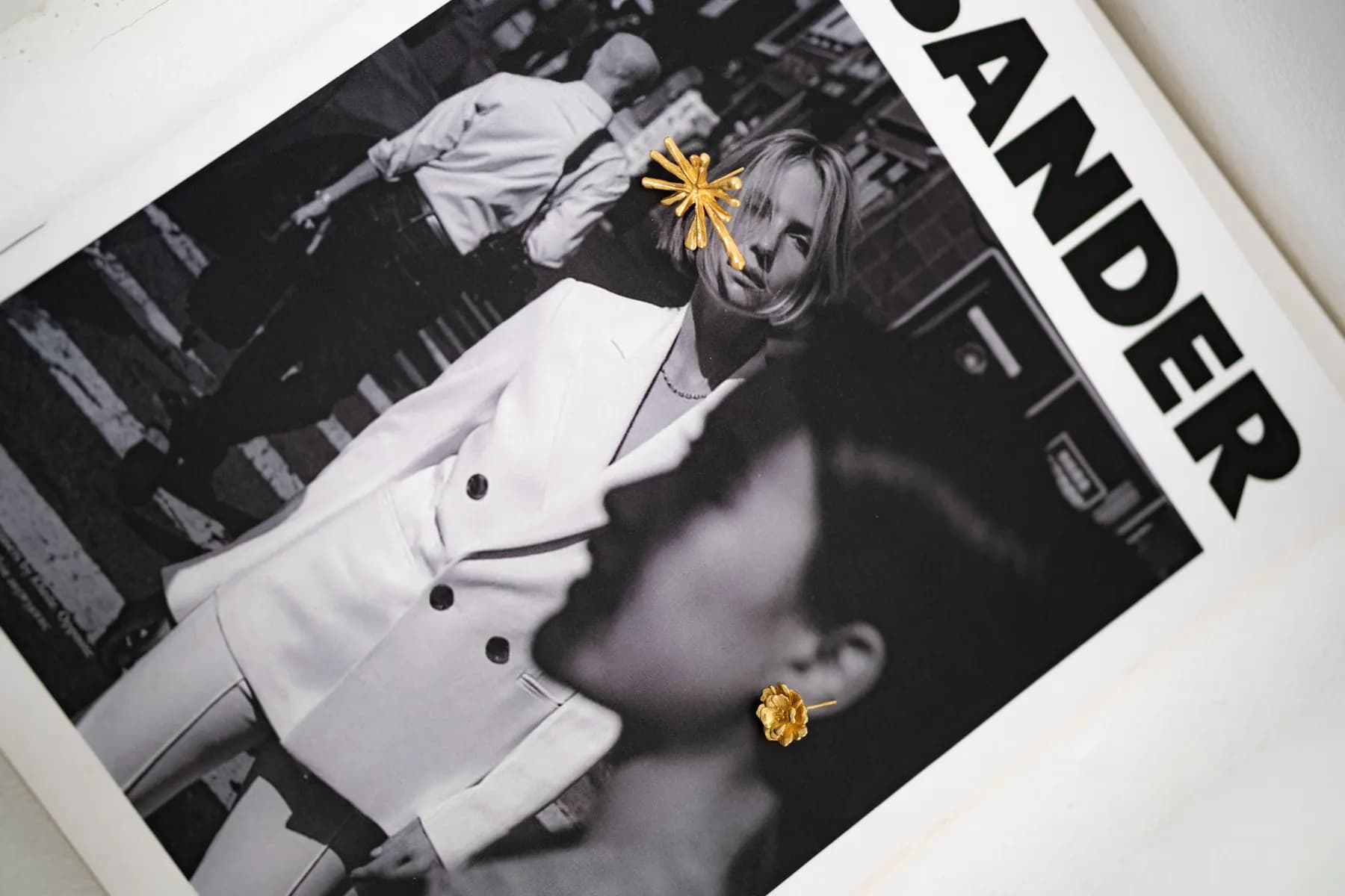 KILAU gold starburst studs placed on a black-and-white magazine spread