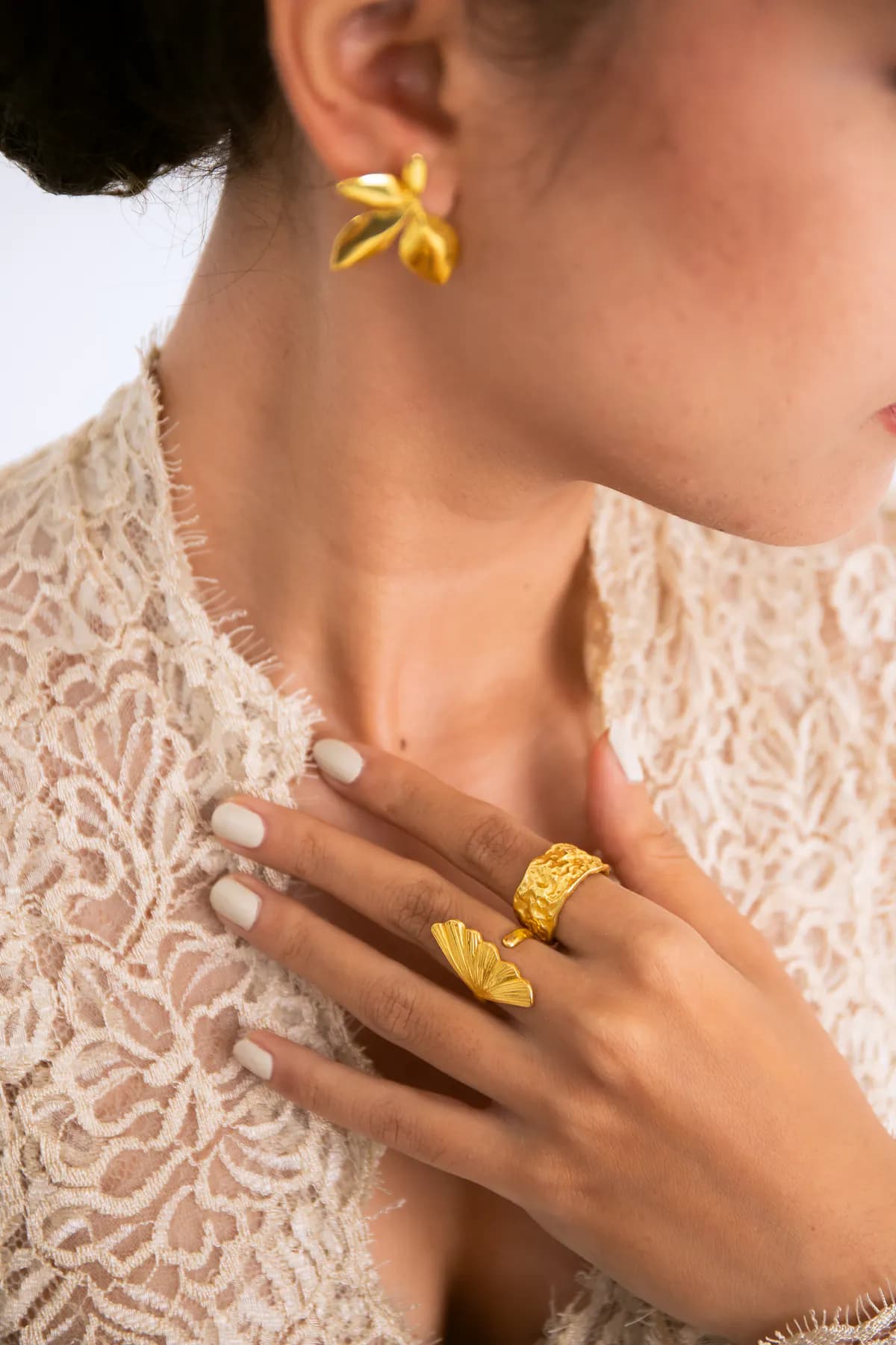 Close-up of a KILAU gold leaf earring and rings on a lace kebaya