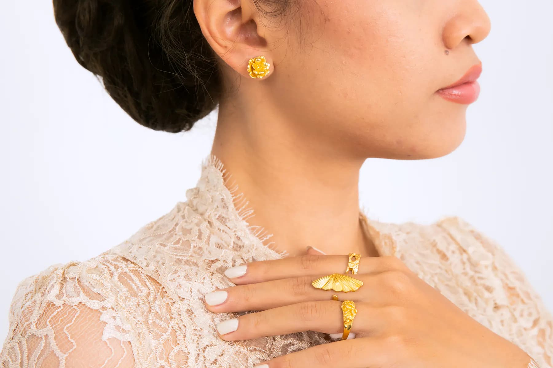 Profile of a model in a lace kebaya wearing a KILAU flower stud and leaf rings