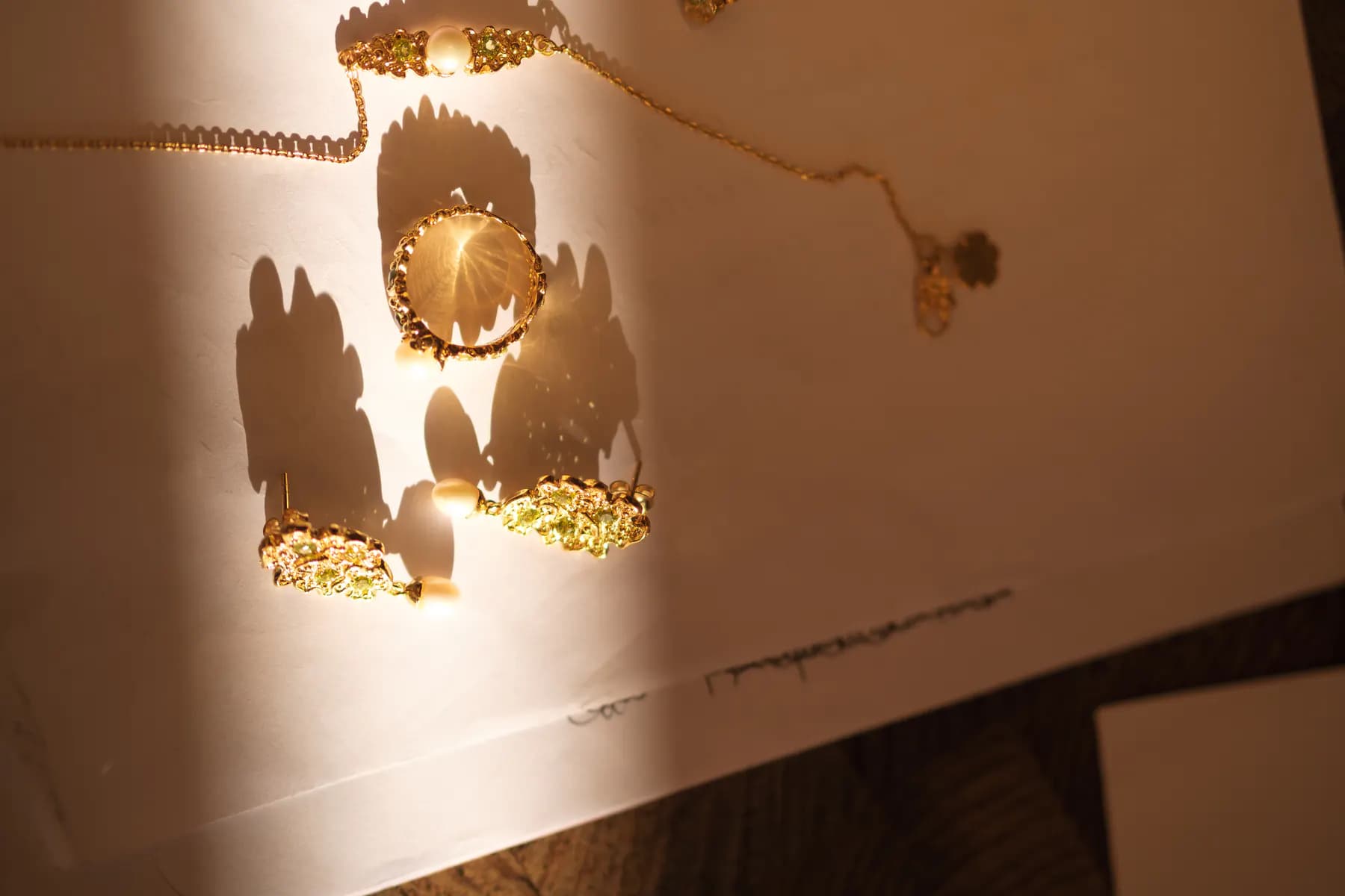 Gold floral rings and necklaces on paper in a shaft of sunlight